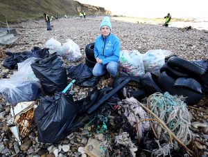 Litter picker on the beach with lots of bin bags full of rubbish